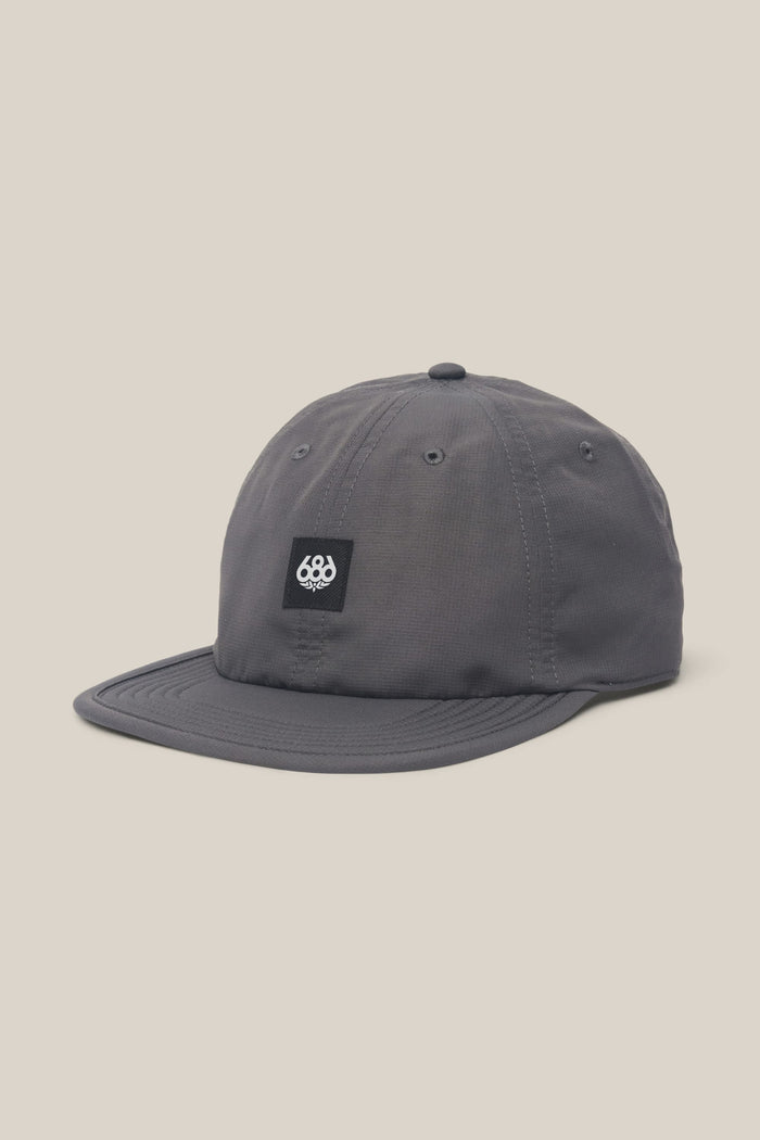 The 686 Low-Pro Adventure Unstructured 6 Panel Hat by 686 is a gray polyester-cotton baseball cap with a black patch and white logo on the front, shown against a plain light beige background.