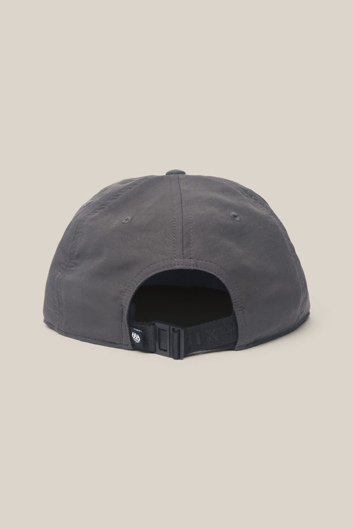 The 686 Low-Pro Adventure Unstructured 6 Panel Hat by 686 is a dark gray men‚Äôs polyester cap, shown from the back with an adjustable strap, black buckle, and small black tag, set against a plain beige background.