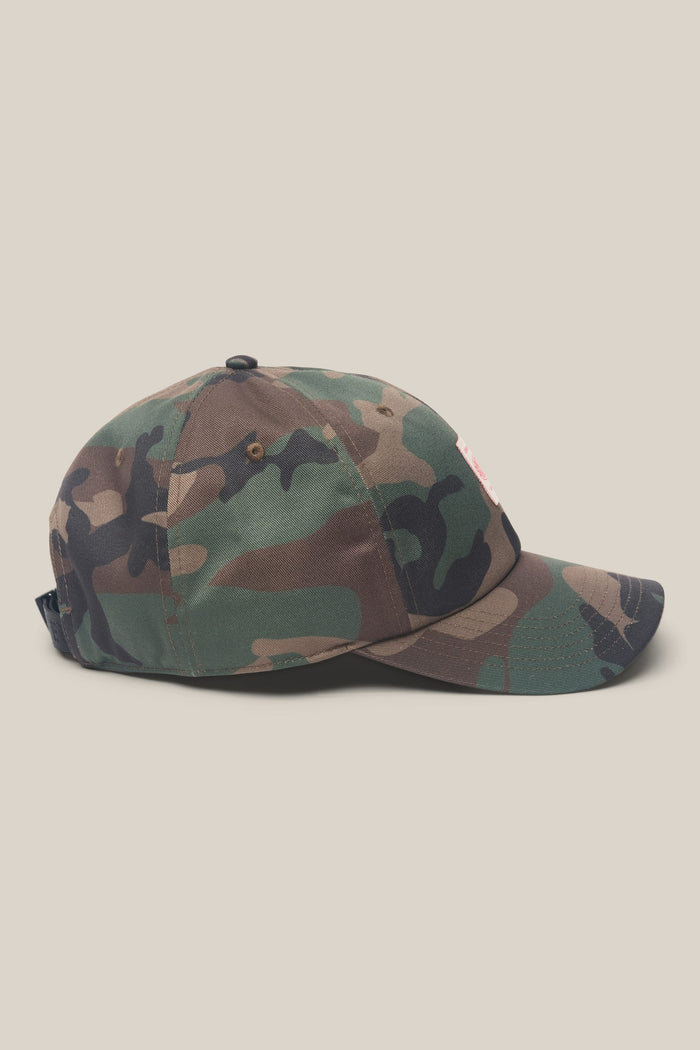 The 686 Low-Pro Unwork Unstructured 6 Panel Hat by 686 is a men's hat featuring a camouflage pattern in shades of green, brown, and black on a light background. Shown from the side, this woven hat is made from a durable polyester cotton blend for comfort and everyday wear.