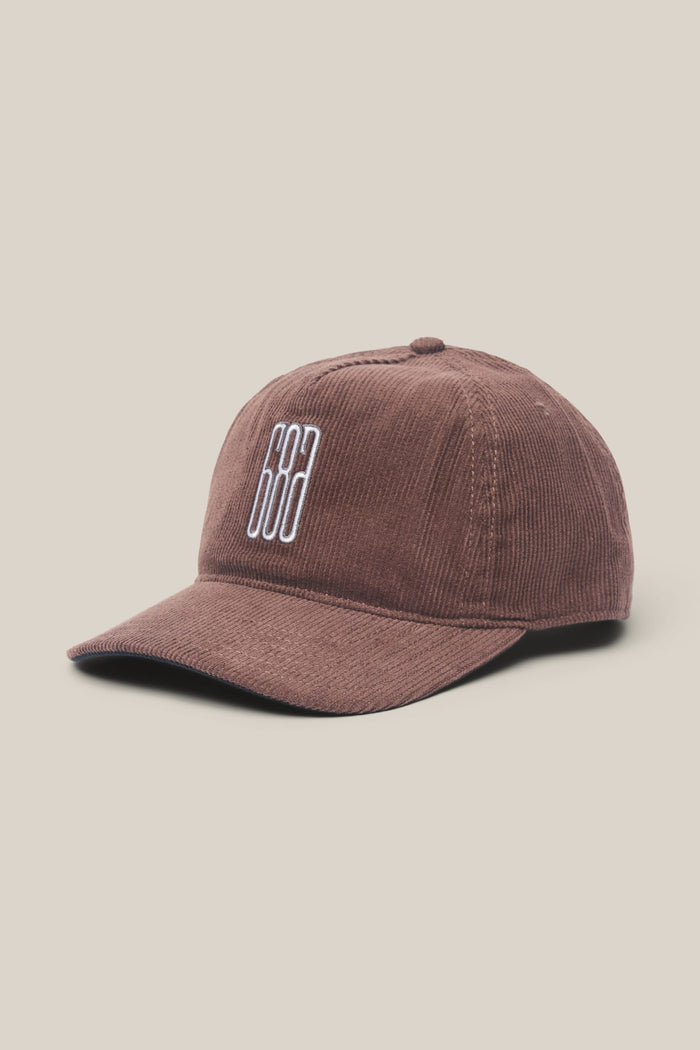 The 686 Mid-Pro Ghost Cord Unstructured 5 Panel Hat by 686 is shown against a light beige background. This men's brown corduroy baseball cap features white embroidered vertical lines on the front and is crafted from a soft polyester-cotton woven material, offering both comfort and timeless style.