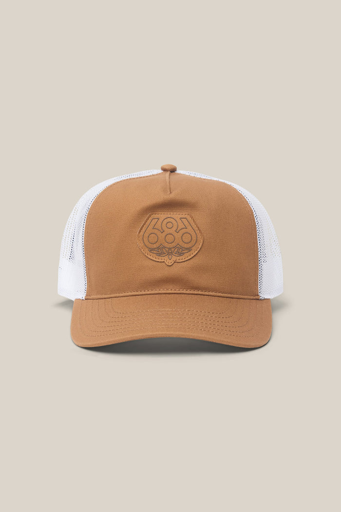 The 686 Mid-Pro Wreath Unstructured 5 Panel Mesh Hat by 686 is a brown and white polyester-cotton woven hat in a classic trucker style, featuring a mesh back and an embroidered logo on the front panel. Displayed on a plain beige background, this men's hat offers casual comfort with timeless design.