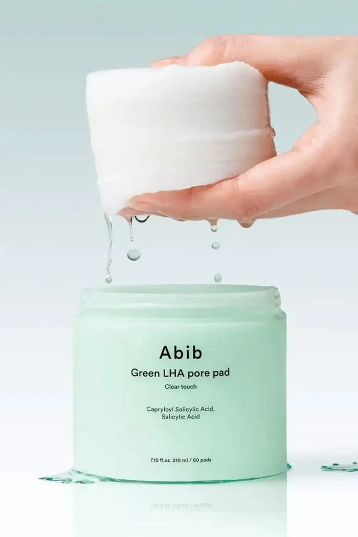 Abib Green LHA pore pad jar with toner-soaked pads lifted above the container, showing dripping essence, Gentle Exfoliating Pads for daily skincare