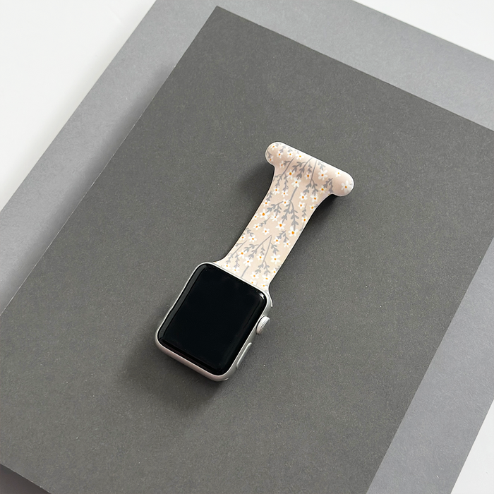 Coconut Lane Apple Watch clip-on fob strap with nude flower pattern on layered dark and light gray paper.