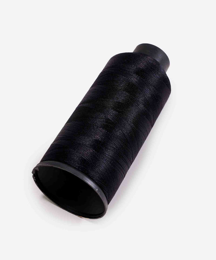 A black spool of thread rests on its side against a plain white background, highlighting its smooth texture.