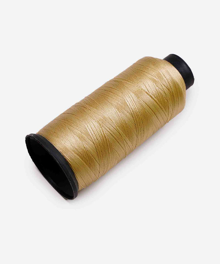 A spool of shimmering gold thread on a black cylindrical core rests against a white background.