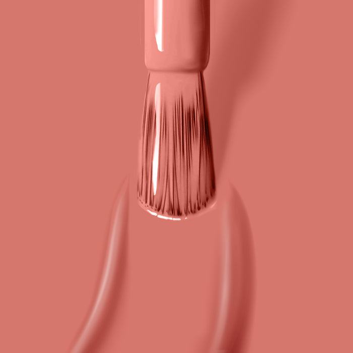 Close-up of a nail polish brush applying a smooth coat of LONDONTOWN's Cactus Coral vegan nail polish against a matching background.