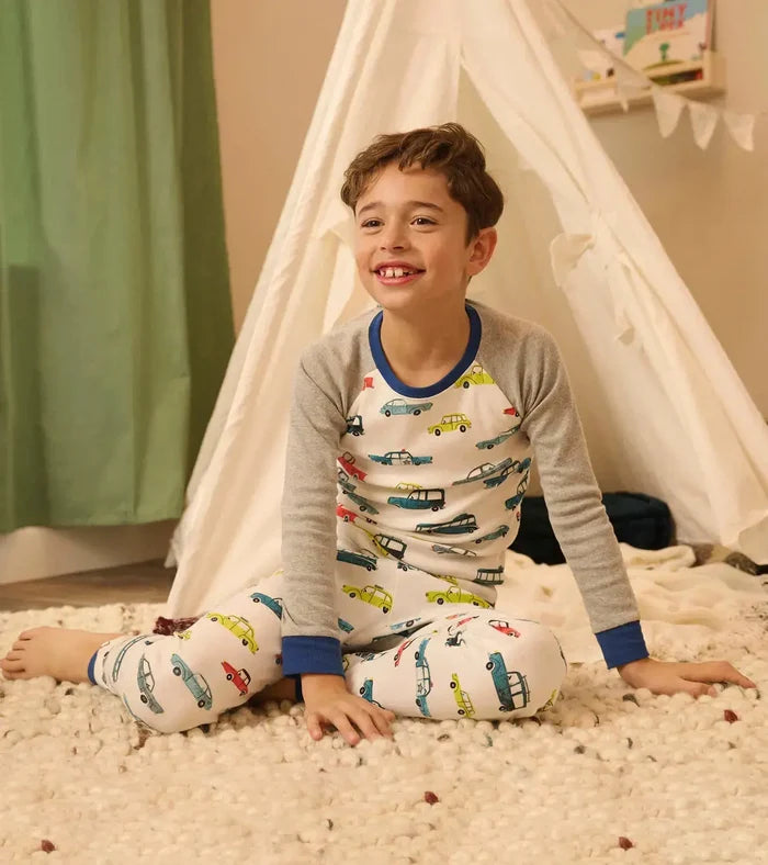 Boy sitting in Hatley boys car pajamas with raglan sleeves and full-length pajama pants.