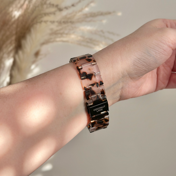 Wrist wearing Coconut Lane LUXE Ivory Tort Fitbit strap with visible branding on the clasp.