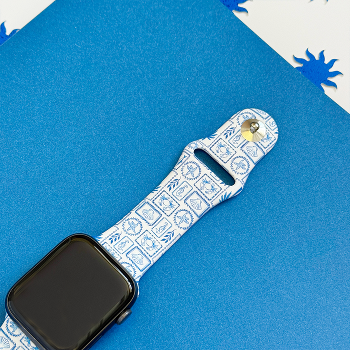 Blue and white patterned Malibu Drive Apple Watch strap by Coconut Lane on a blue textured surface.
