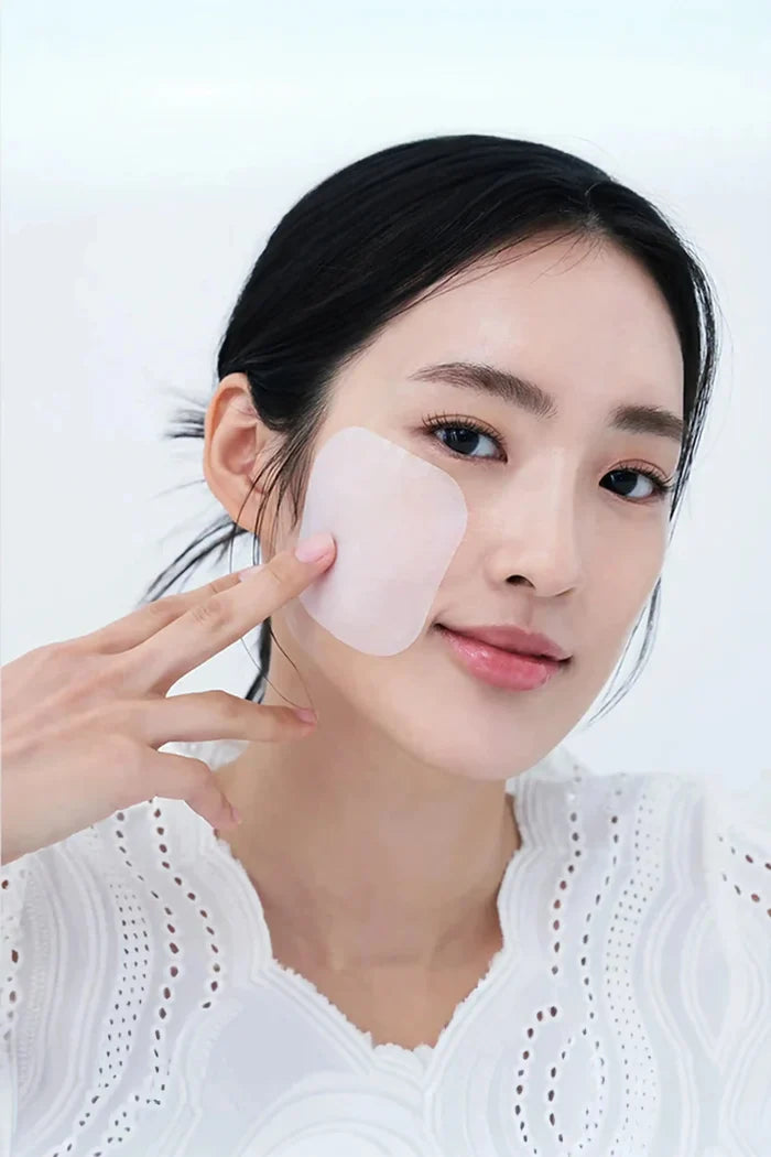 A model applying a Mediheal Vitamide toner pad to her cheek, demonstrating effective skincare for dull skin to achieve a radiant glow.