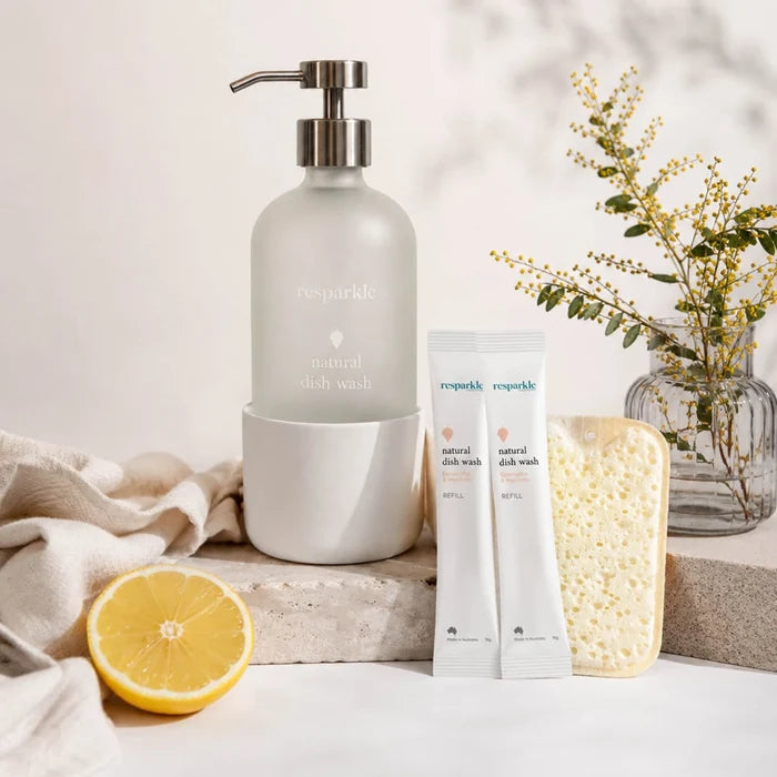 Set of natural dish wash products with a lemon and sponge on a light surface.