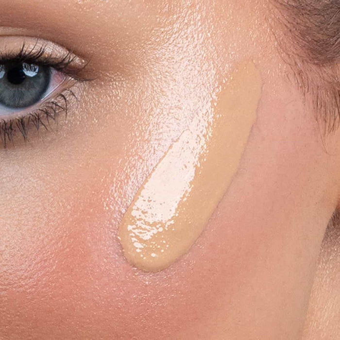 Close-up of bronzing drops applied to skin.
