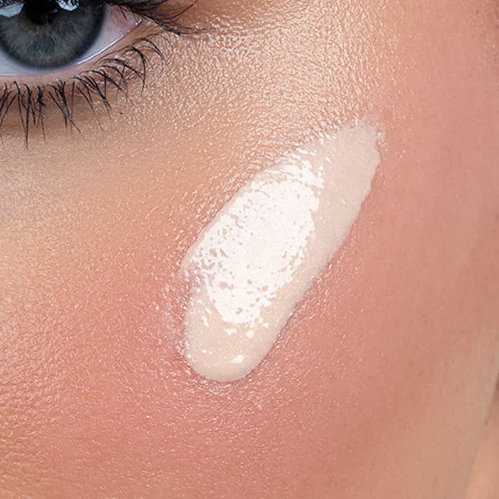 Close-up of a person's eye with glow drops applied to the cheekbone.