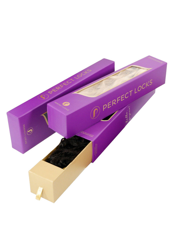 Three sleek purple Perfect Locks boxes, stacked at angles, with one partially open to reveal dark hair extensions inside.