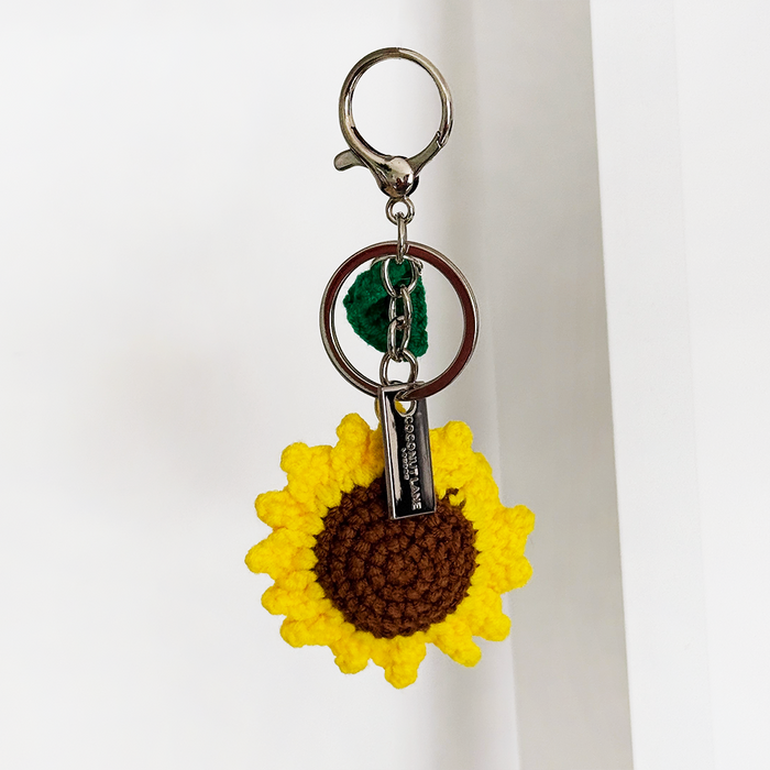 Yellow crocheted sunflower and green leaf on a metal ring bag charm from Coconut Lane.