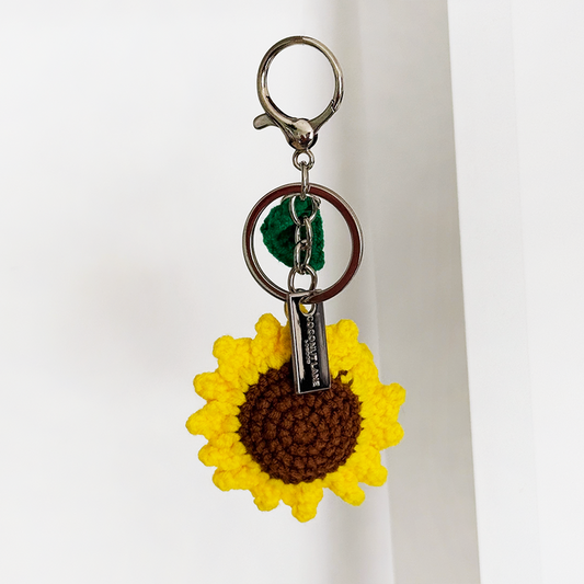 Yellow crocheted sunflower and green leaf on a metal ring bag charm from Coconut Lane.