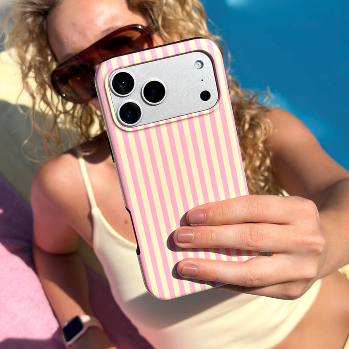 Person holding a tough phone with a pink and yellow striped case by a pool