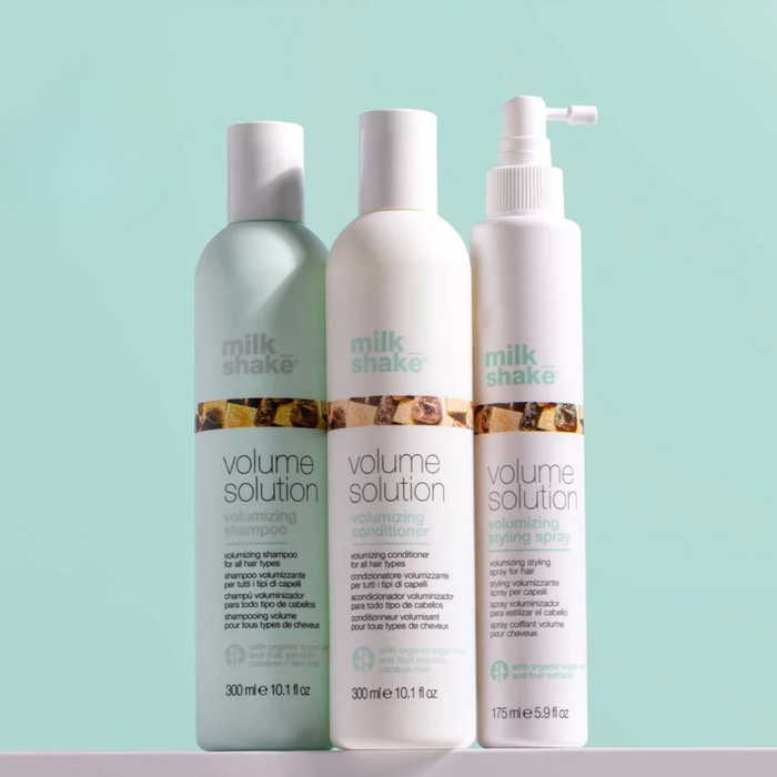Three bottles of milk_shake  Volume Solution hair care products on a light blue background
